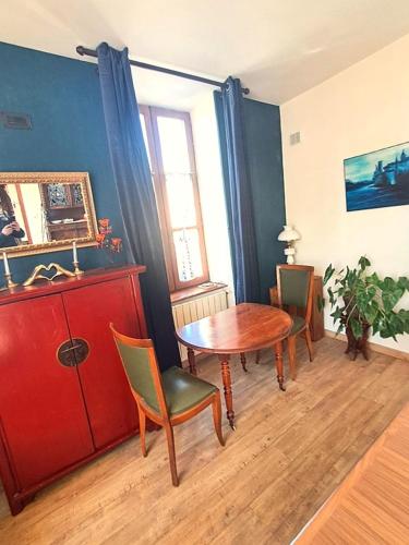 Cette chambre comprend une table, des chaises et une armoire rouge. dans l'établissement Les Chambres de la Violette, à Grenier-Montgon