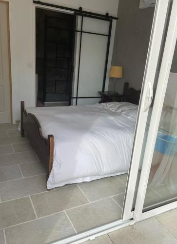 a bedroom with a bed with white sheets and a window at Chambre privée in Contes