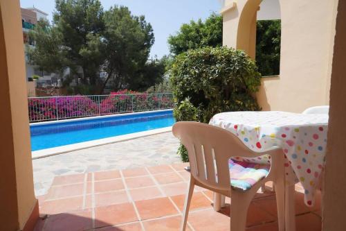 una mesa y sillas en un patio junto a la piscina en Las Flores de Burriana, en Nerja