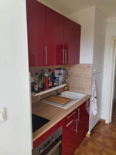 une cuisine avec des armoires rouges et un évier dans l'établissement T2 bord de mer, à Hyères