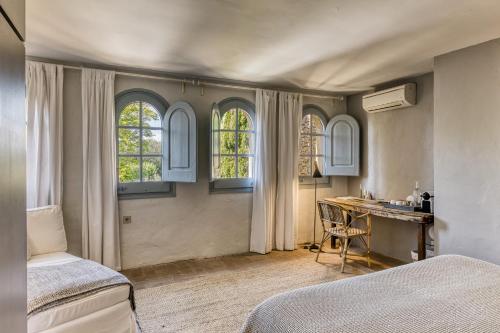 a bedroom with two beds and a desk and two windows at Les Hamaques Hotel in Viladamat