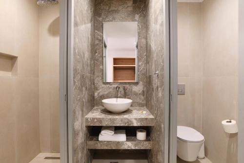 a bathroom with a sink and a toilet and a mirror at Pefkos Village Resort in Pefki Rhodes
