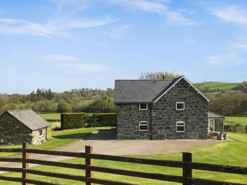 a stone house with a fence in front of it at Plas Madog in Llanuwchllyn