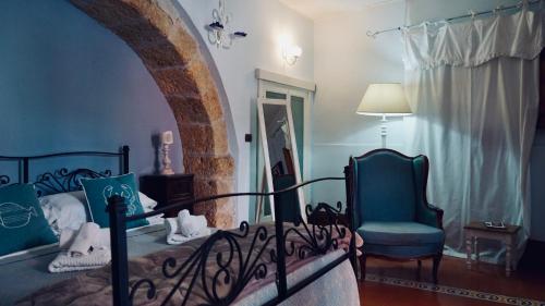 a bedroom with a bed and a chair and a window at Antica Dimora San Girolamo in Licata