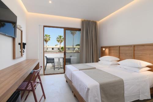 a hotel room with a bed and a balcony at Pefkos Village Resort in Pefki Rhodes