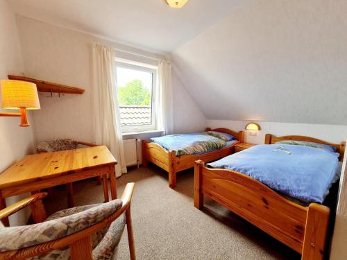 a bedroom with two beds and a table and a window at Ferienwohnung "Lütt Welt" in Welt