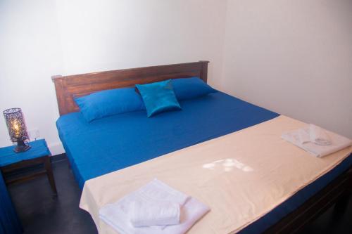 a bedroom with a bed with blue pillows at Araliya Villa Hikkaduwa in Hikkaduwa