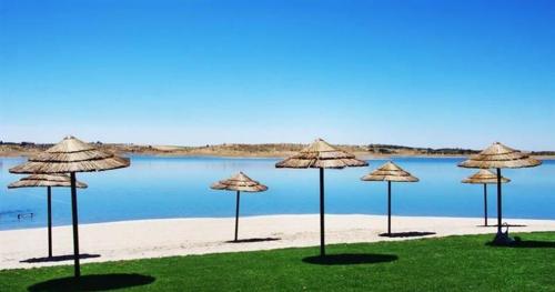 un gruppo di ombrelloni di paglia su una spiaggia di Casa da Oliveira a Reguengos de Monsaraz