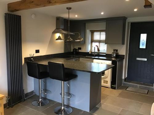 a kitchen with a large island with two bar stools at Renovated 2 bed Cottage in Ulverston, Garden with Views in Ulverston