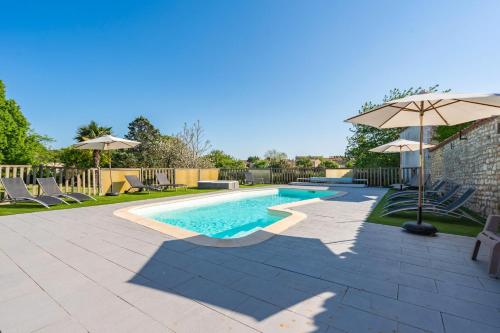une piscine avec des chaises et un parasol dans l'établissement Les gîtes du logis, à Saint-Romain-de-Benet