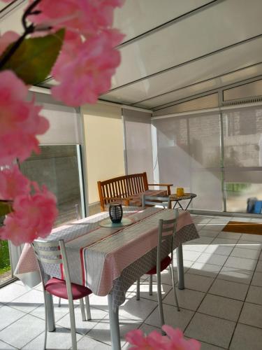 une table et des chaises dans une pièce ornée de fleurs roses dans l'établissement Maison 3 étoiles proche des plages, à Pont-lʼAbbé