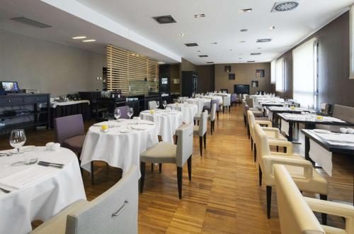 a dining room with white tables and chairs at NH Milano Fiera in Rho