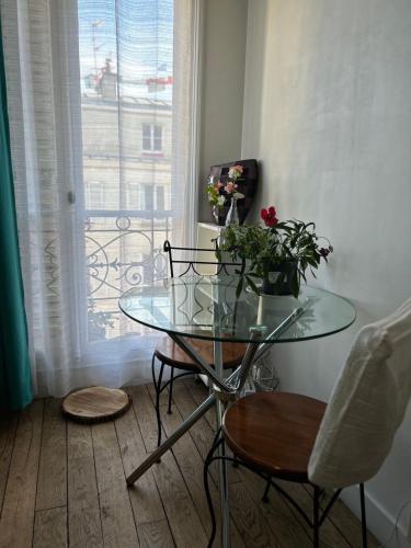 une table en verre avec des fleurs dans une chambre avec une fenêtre dans l'établissement StPaul2 Appt Rive Droite centre Marais, à Paris