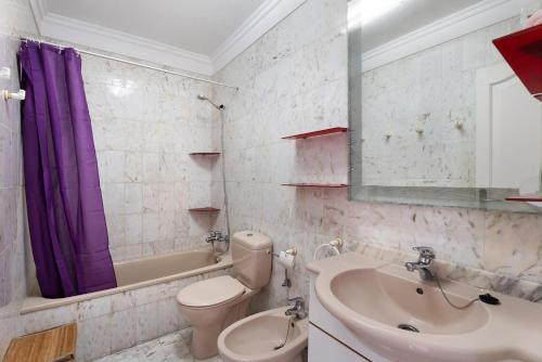 a bathroom with a sink toilet and a purple shower curtain at Al Mar Los Gigantes in Puerto de Santiago