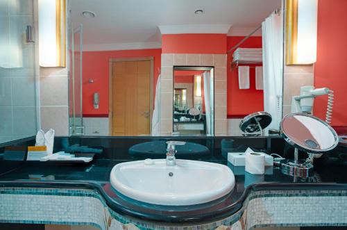 a bathroom with a white sink and a red wall at Oryx Hotel in Abu Dhabi