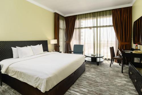 a hotel room with a large bed and a desk at Oryx Hotel in Abu Dhabi