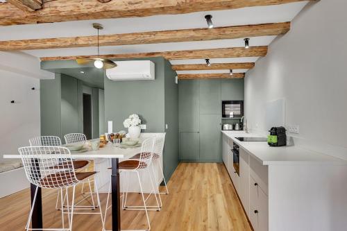 - une cuisine avec une table et des chaises blanches dans l'établissement Le Gambetta - Élégance et Confort - Vue sur la Place Stanislas, à Nancy