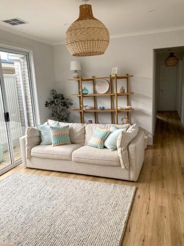 a living room with a white couch and a rug at Seaside Daisy 3 Bedrooms 6 Beds in Goolwa