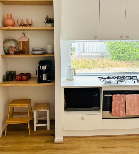a kitchen with a stove and a counter top at Seaside Daisy 3 Bedrooms 6 Beds in Goolwa