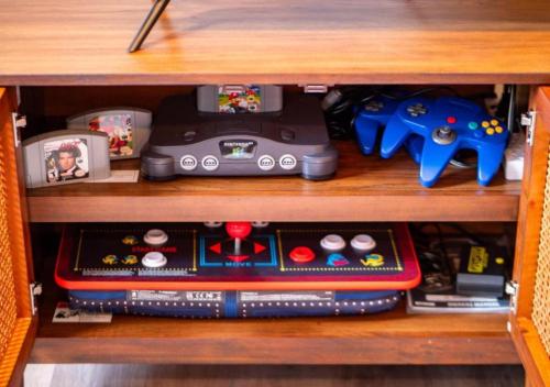 a shelf with consoles and video game controllers at Hot Tub N64 Mins to Downtown Sleeps 8 in Cleveland