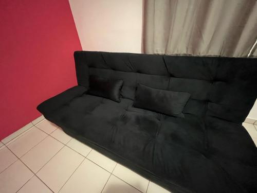 a black couch with two pillows in a room at Aconchegante Apt Alto Umuarama Uberlândia in Uberlândia