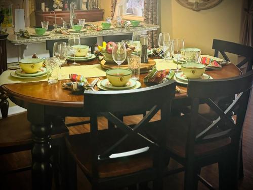 a wooden table with plates and wine glasses on it at Paradise at Peaceful in Palm BayTiki Bar Pool Spa 4 Bedroom 2 Full Bathrooms 2 half Bathrooms in Palm Bay