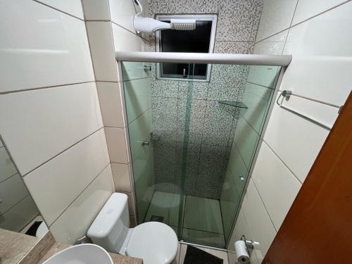 a bathroom with a toilet and a glass shower at Aconchegante Apt Alto Umuarama Uberlândia in Uberlândia