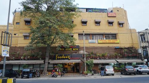 a large yellow building with cars parked in front of it at Sky Star Hotel in Amritsar