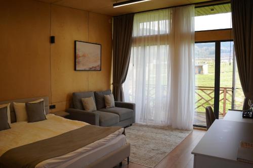 a bedroom with a bed and a couch and a window at Eco-hotel AQBULAQ in Kaynazarka