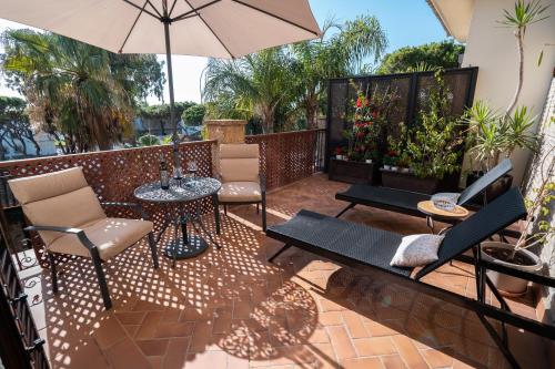 a patio with a table and chairs and an umbrella at Hotel Azalea Playa in Chiclana de la Frontera