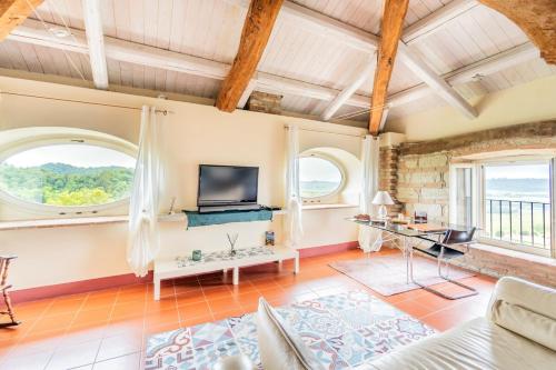a living room with a tv and two windows at Cascina Petricore - Elegante dimora tra le colline del Monferrato in Moncalvo