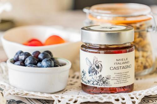 a jar of fruit jam next to a bowl of blueberries at Cascina Petricore - Elegante dimora tra le colline del Monferrato in Moncalvo