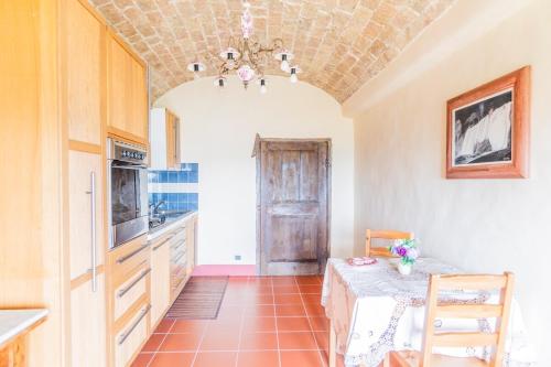a kitchen with a table and a chandelier at Cascina Petricore - Elegante dimora tra le colline del Monferrato in Moncalvo