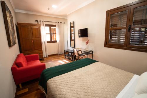 a bedroom with a bed and a red chair at Hotel Azalea Playa in Chiclana de la Frontera