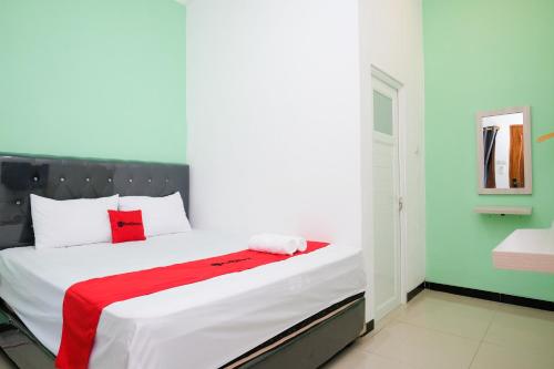 a bedroom with a bed with a red blanket on it at RedDoorz near Candi Prambanan 3 Yogyakarta in Kenaran