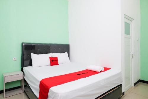 a bedroom with a bed with a red blanket on it at RedDoorz near Candi Prambanan 3 Yogyakarta in Kenaran