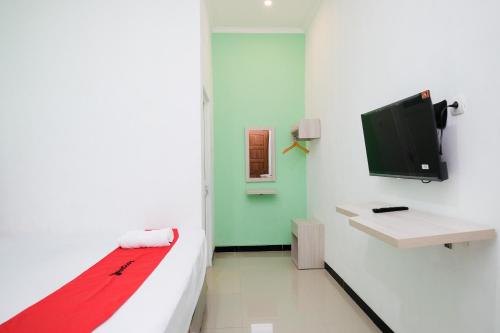 a room with a bed and a flat screen tv at RedDoorz near Candi Prambanan 3 Yogyakarta in Kenaran