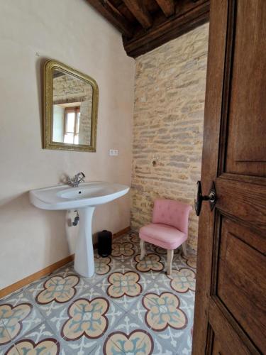 La salle de bains est pourvue d'un lavabo et d'une chaise rose. dans l'établissement MAISON EN PIERRE type CHATEAU, à Lœuilley