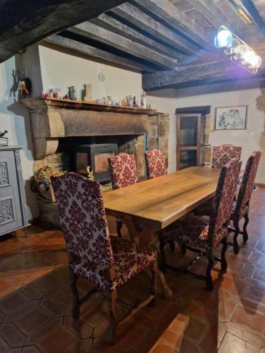 une table et des chaises en bois dans une pièce avec une cheminée dans l'établissement MAISON EN PIERRE type CHATEAU, à Lœuilley