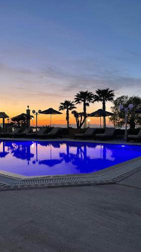 a large blue pool with palm trees and umbrellas at EONA BEACH RESORT by Greek Pride in Skála Neón Epivatón