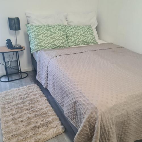 a bed with a blanket and a night stand next to it at St Georgen im Attergau ein Zimmer Wohnung in Sankt Georgen im Attergau