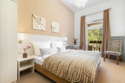 a bedroom with a bed and a chair and a window at Hotel Luise in Bad Bergzabern