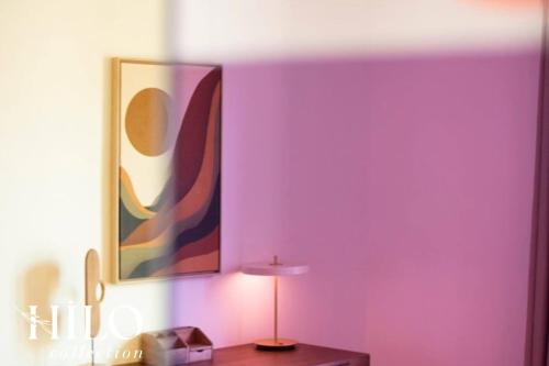 une pièce avec un mur violet avec une lampe et un tableau dans l'établissement HILO Suite Paris Stendhal - 6pers - 70m2, à Paris