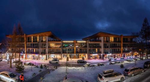 a large building with cars parked in a parking lot at Hrebienok Apartman D4 in Vysoké Tatry