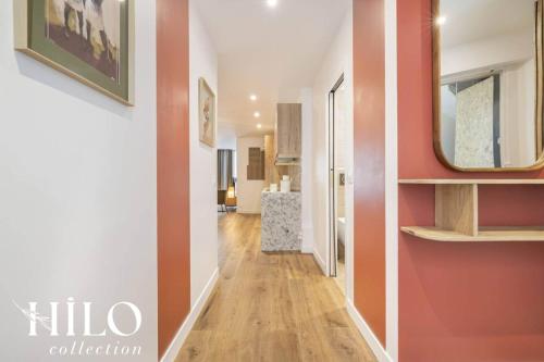 un couloir avec un mur rouge et un miroir dans l'établissement HILO Suite Paris Balzac - 6 pers - 63m2, à Paris