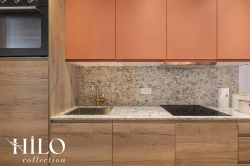 une cuisine avec des armoires orange et un évier dans l'établissement HILO Suite Paris Balzac - 6 pers - 63m2, à Paris
