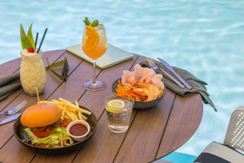 a table with a sandwich and french fries and a drink at Peppers Beach Club in Port Douglas