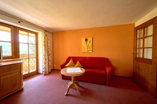 a living room with a red couch and a table at Ferienhof Almfrieden in Balderschwang