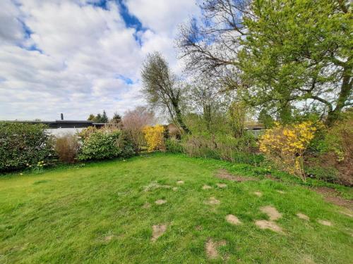 a grassy yard with trees and bushes on a cloudy day at Lütt Haffhus - Haffkrug in Haffkrug