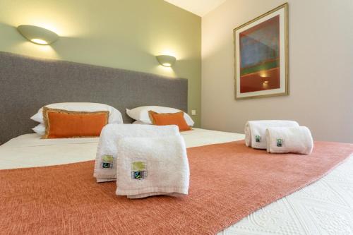 a bedroom with two beds with towels on them at Logis Hôtel La Bastide De Grignan & Restaurant "La Chênaie" in Grignan